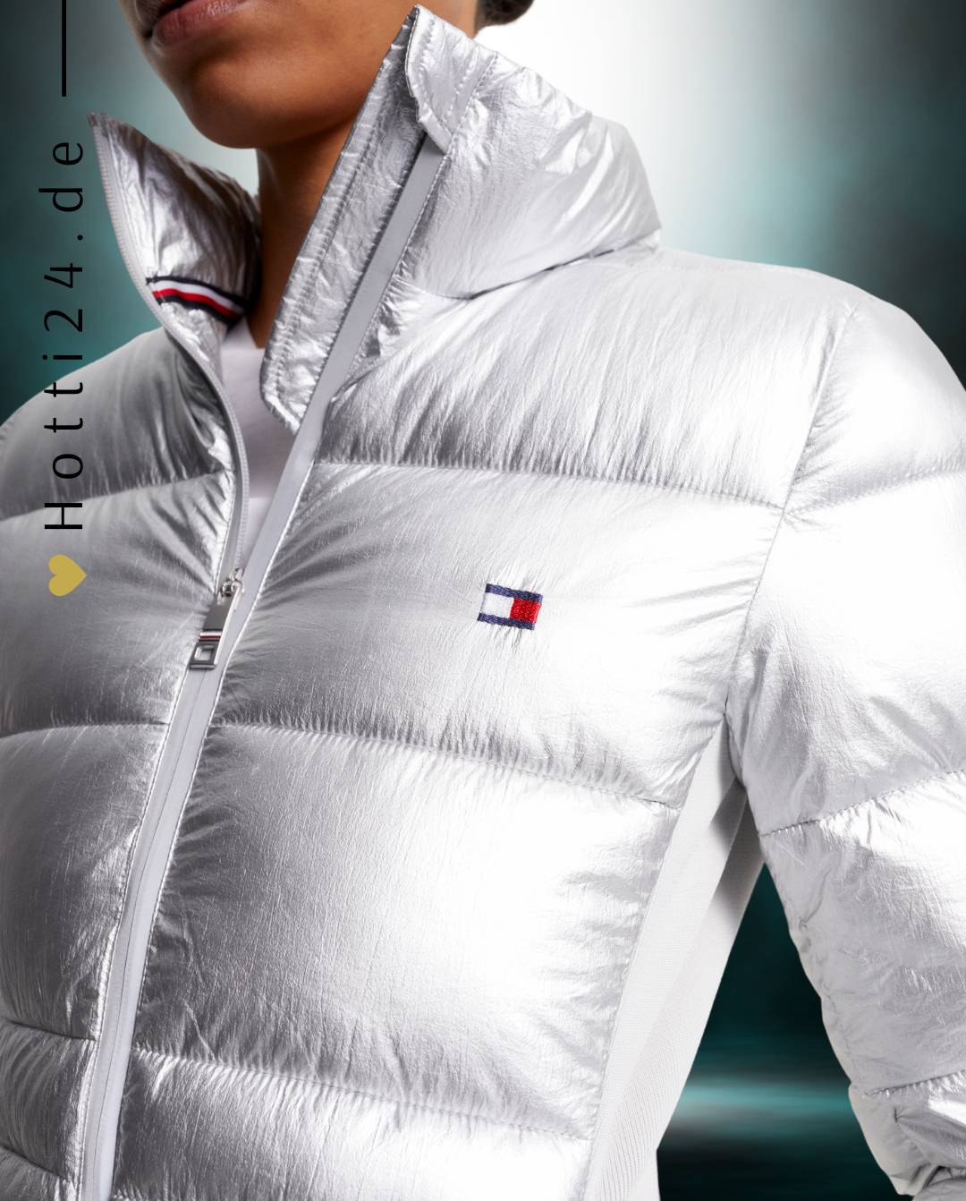 amen-Jacke von Tommy Hilfiger mit der Bezeichnung "Puffer TH08WJAC599-044" in der Farbe Silber. Diese Jacke ist auf der Webseite www.hotti24.de erhältlich. Sie wurde speziell für Damen entworfen, um sowohl Stil als auch Wärme zu bieten.  Zusätzlich sind in der Datei Bilder der Jacke aus verschiedenen Blickwinkeln enthalten: von vorne, von der Seite und von hinten. 