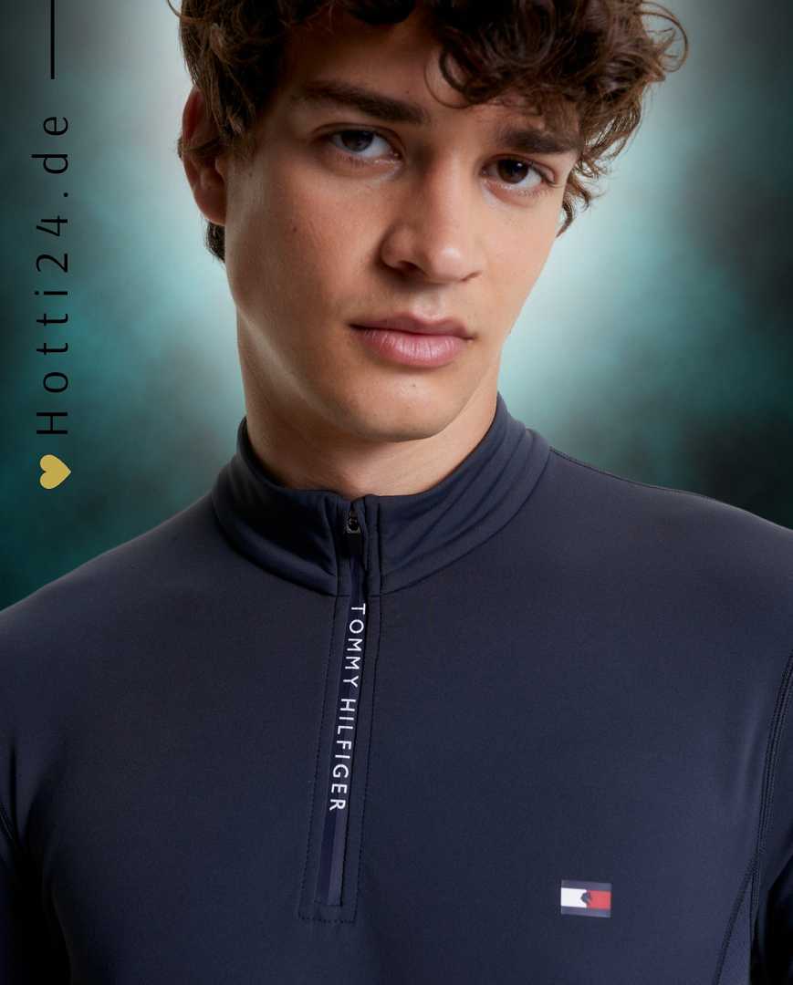 Herren-Trainingshirt von Tommy Hilfiger mit der Bezeichnung "Thermo TH08MLZS471-042" in der Farbe Grau. Das Trainingshirt ist auf der Webseite www.hotti24.de verfügbar. Dieses spezielle Shirt wurde entwickelt, um während des Trainings Wärme zu bieten und gleichzeitig Komfort zu gewährleisten.  In der Datei sind auch Bilder des Trainingshemds aus verschiedenen Blickwinkeln enthalten, einschließlich der Vorderseite, der Seite und der Rückseite. 